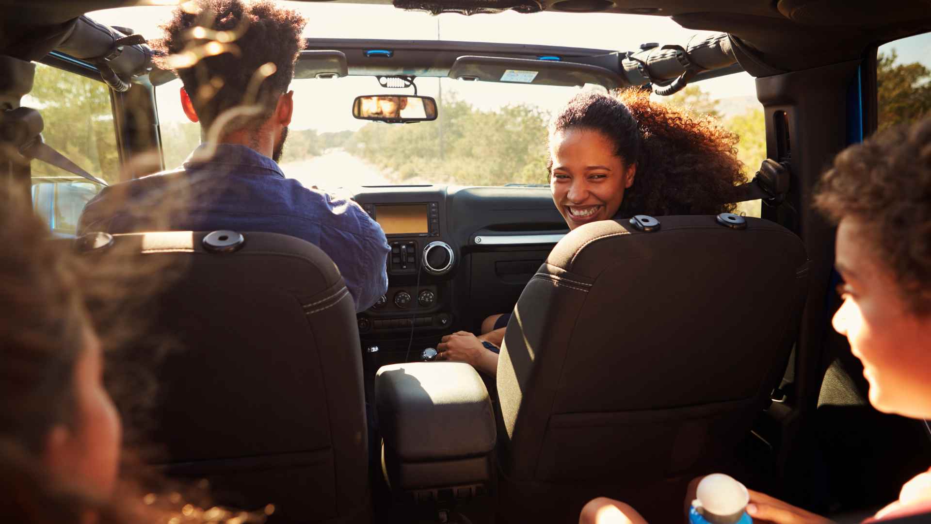 Teenager and younger sibling laughing together playing a car game on a long drive