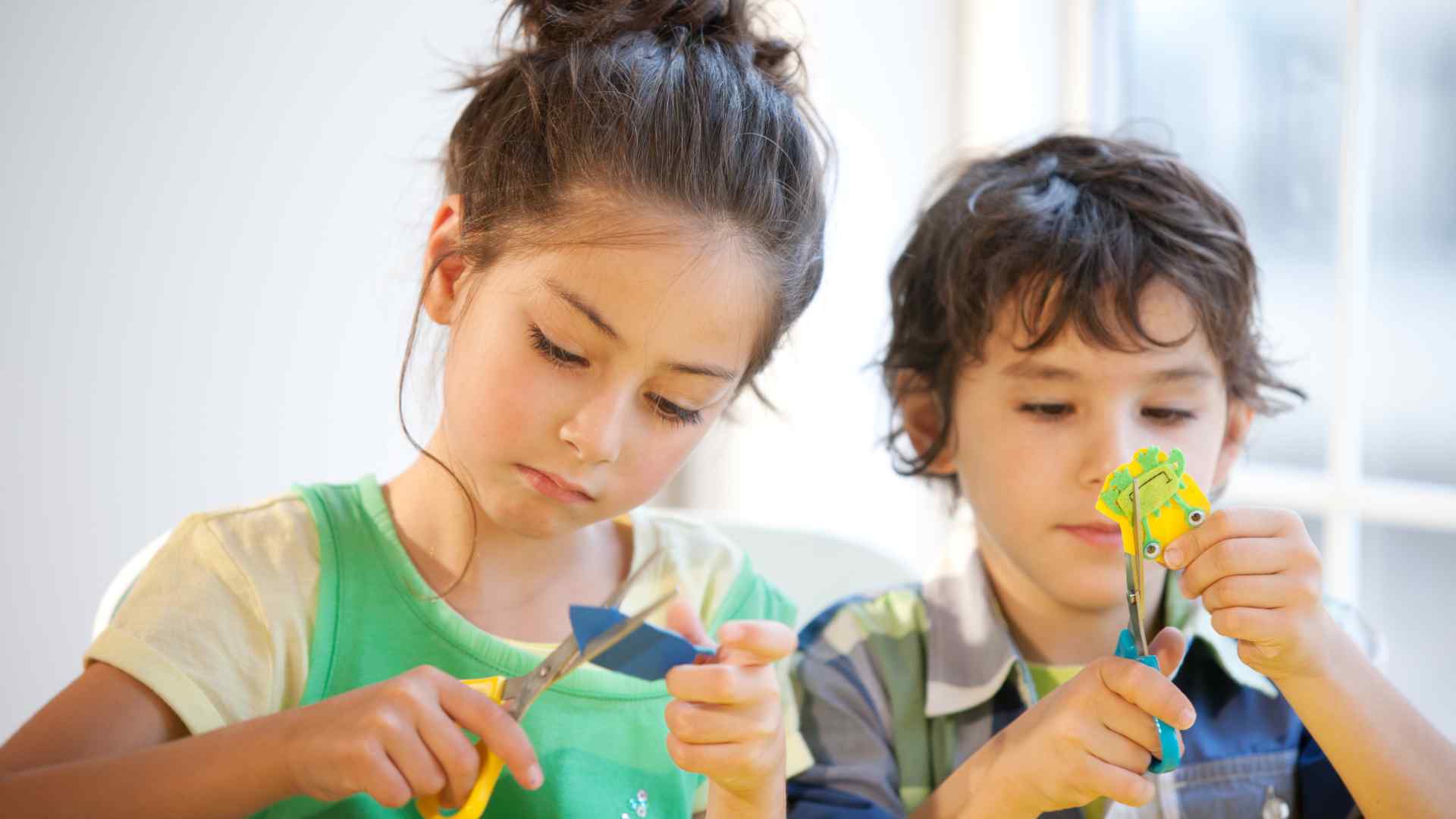 Child folding a paper airplane at a kitchen table using printer paper