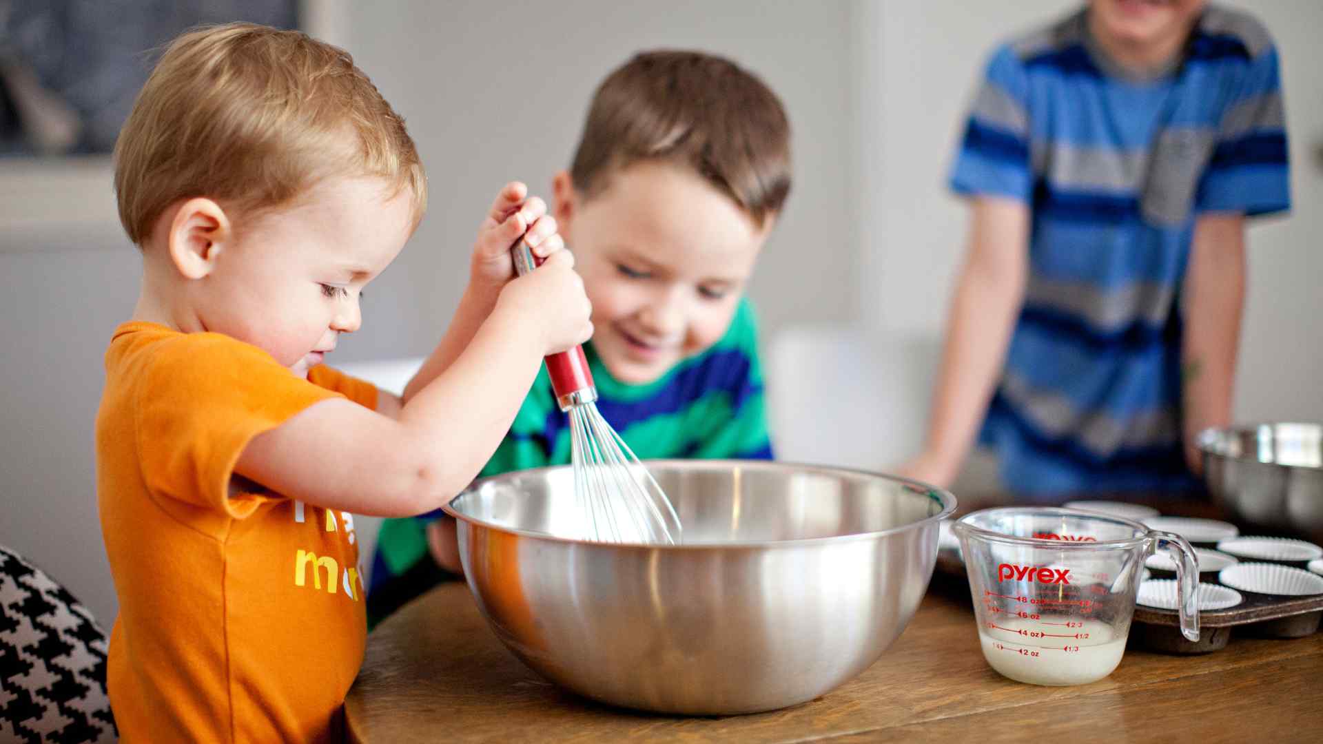 Kid's hands mixing a red cabbage pH indicator with vinegar and baking soda in clear cups