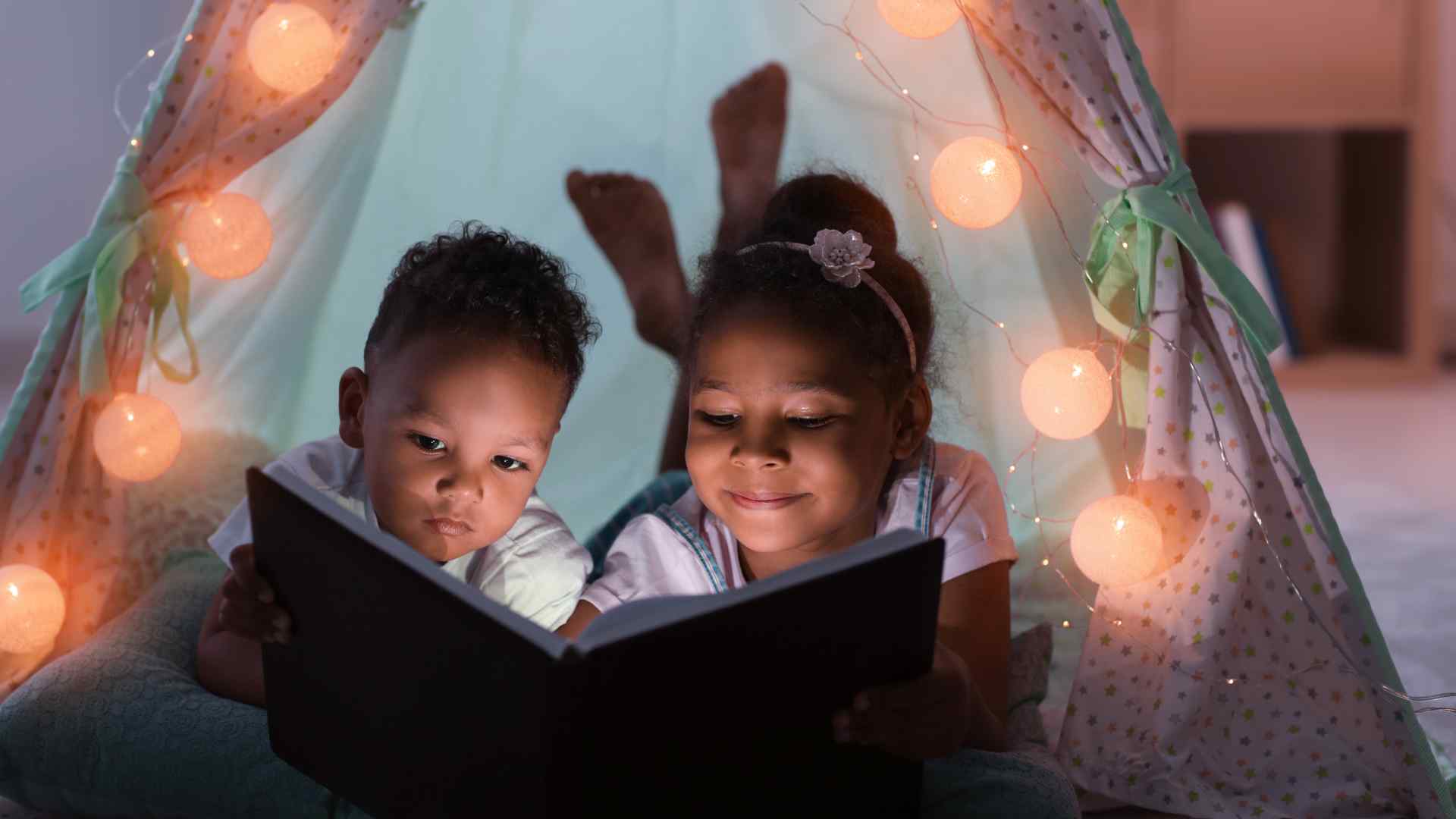 Parent reading a board book aloud to a toddler curled up on their lap
